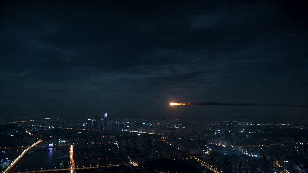 A glowing asteroid enters the atmosphere above a sprawling…