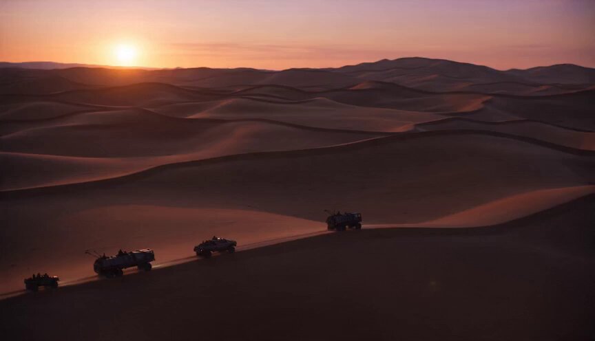 Massive sci-fi desert world at sunset. A convoy of…